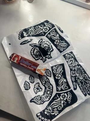 Henna cone och mallar för kroppskonst - Säljer en henna cone från Dollar och tillhörande mallar för att skapa snygga och detaljerade hennamönster på händer och fötter. Perfekt för dig som vill testa temporära tatueringar med traditionella motiv. Mallen är svartvit och konen är brunröd.