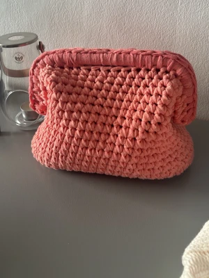 Virkad clutch väska  - Virkad clutchväska med handtag i korallfärg