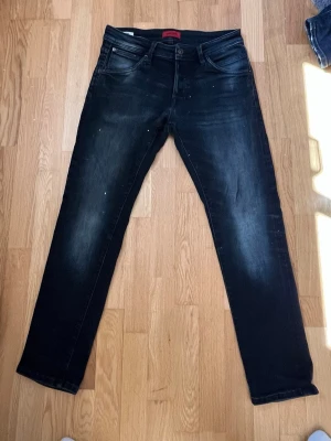 Jack and Jones jeans - Storlek 31x30. Modell slim/glenn. Snygga svarta slim fit jeans med tvättade detaljer och klassisk femficksmodell. Jeansen har en lätt stretchig känsla och subtila slitningar för en cool look. Passar perfekt till en avslappnad stil och är enkla att matcha med olika plagg.