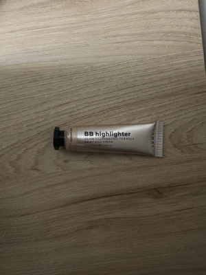 BB highlighter i tub - BB highlighter i en beige tub med svart skruvkork. Produkten har en glow illuminating formula och ger en daggig, silkeslen finish. Tuben är kompakt och enkel att ta med i necessären. Perfekt för att skapa lyster i ansiktet.