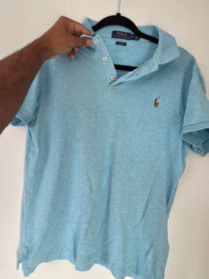 Ljusblå pikétröja från Polo Ralph Lauren - I mycket bra skick. Använd fåtal ggr. Perfekt till jeans eller shorts.