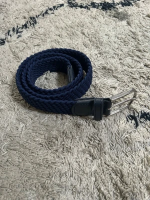 Mörkblått flätat bälte med skinn - Snyggt mörkblått flätat bälte med detaljer i skinn och silverfärgat spänne från John Henric😁