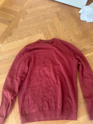 Vinröd tröja från Massimo Dutti - Vinröd tröja från Massimo Dutti i mjukt material. Klassisk rund halsringning och ribbade muddar vid ärmslut och nederkant. Enkel och stilren design som passar perfekt till jeans eller chinos. Storlek medium. 