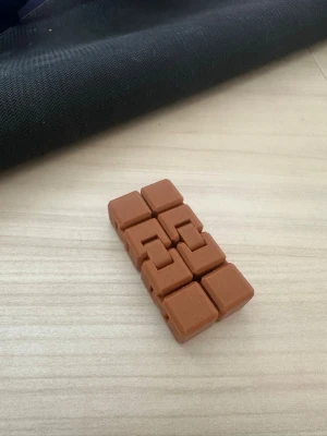 Brun fidget cube i plast - En brun fidget cube i plast med åtta sammankopplade delar som kan vikas och snurras på olika sätt. Perfekt för att sysselsätta händerna och minska stress. Smidig att ha i fickan eller på skrivbordet.