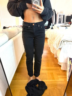Svarta high waist mom jeans - Säljer ett par svarta mom jeans med hög midja och raka ben. Jeansen har klassisk femficksdesign och knappgylf. Snygg passform som sitter tajt över höfterna och blir lite lösare nedtill. Perfekta till en avslappnad och trendig look.