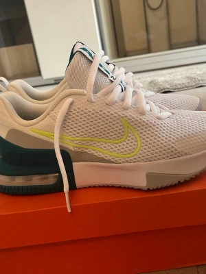 Nike Air Max vita sneakers - Nike Air Max sneakers helt nya, direkt från lådan i vitt meshmaterial med limegrön swoosh och detaljer i turkos och grått. Skorna har en synlig Air Max-dämpning i hälen och klassisk låg siluett. Perfekta för dig som gillar sportig och fräsch stil