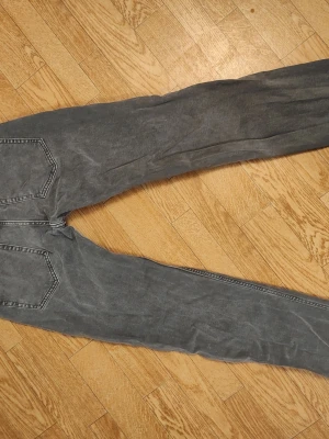 Grå raka jeans med bakfickor 32/32 - Snygga grå jeans med raka ben och klassiska bakfickor. Jeansen har en enkel design med kontrastsömmar och svart patch vid linningen. Perfekta för en avslappnad och stilren look. Stl herr 32/32