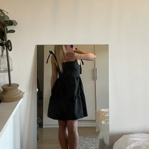 Svart klänning - Så fin svart lite volangklänning med rosetter på banden som man kan knyta själv. Använd endast en gång och är jättesöt till sommaren🤍