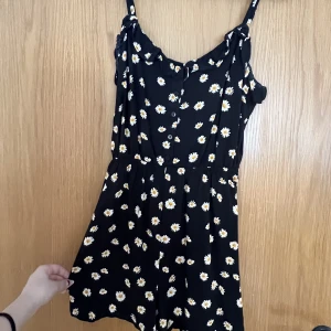 Blommig Playsuit - Playsuit med blommor på från Bershka! Den är super söt nu på sommaren när man ska på lunch eller stranden. Den är lätt att ta på och av. I mycket bra skick. Säljer bara pga att den inte kommer till användning 💕