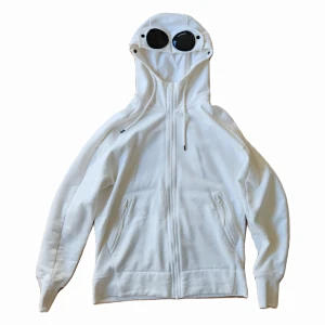 CP Company Hoodie - Säljer den då jag blivit lite för rund för den hehehe. Knappt använd. Passformen är relativt slim fit. Köpt på sweet & tender i Helsingborg år 2021. Nypris 3299kr. Skick 8.5/10, inga hål inga skador, finns en liten fläck på ena ärmen.