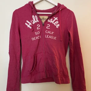 Hollister  - Hollister zip hoodie med luva och ficka framtill. Fin cerise färg.
