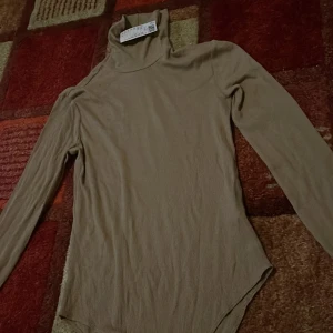 Body med hög hals - En body med hög hals från H&M. Helt oanvänd med prislappen på. Har köpt två likadana och priset kan diskuteras