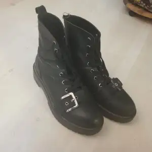 Svarta kängor skulle passa perfekt i den med mer gotisk stil, påminner om combat boots, slitna och ena 
