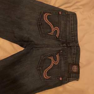 As snygga Lågmidjade bootcut jeans storlek 32 från rock&republic med lila detaljer på bakfickorna 