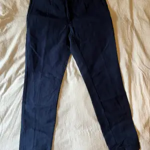 Byxor i linne/bomull-blandning marinblått, nyskick. Strl 40 motsvarande 29/30 i jeans. Sytt slag nedtill.