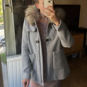 Grå kappa - Grå kappa i storlek S, passar även XS. Realistisk och fin fuskpäls ingår.   Den är knappt använd. Smått nopprig på insidan av armen, därav priset men annars väldigt fint skick.  Nypris 1799kr.