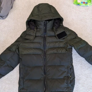 Boss jacka grön - En höst/vinterjacka från boss I färgen mörkgrön, har haft den här jackan i några år och kan intyga att den är väldigt varm för att säljas som en höst modell, har använt den två vintrar. Varmare än Canada goose enligt mig