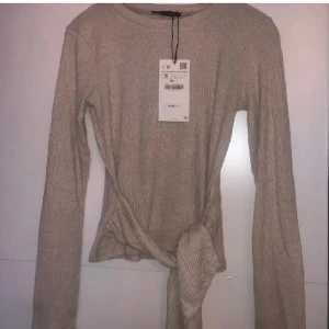 Tröja med knut från zara - (LÅNAD BILD)  Jättefin långärmad tröja från zara med snören man kan knyta fram och baktill.  Storlek: L men liten i storleken men passar olika storleksr för den e strechig  Säljer för den ej kommer till använding längre, jättebra skick! 