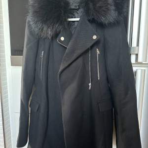 Svart längre kappa med fuskpäls (avtagbar) från Zara. Stl XS, knappt använd så i fint skick!