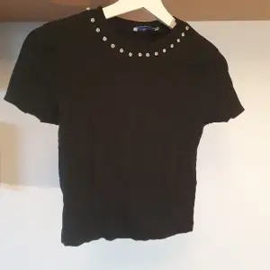 Svart topp från Zara i t-shirt-modell med strass kring halsen. Sparsamt använd! 