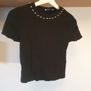 Svart topp från Zara med strass - Svart topp från Zara i t-shirt-modell med strass kring halsen. Sparsamt använd! 