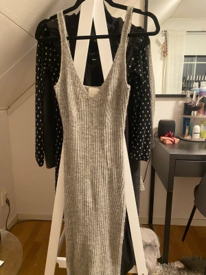 H&M stickad klänning - H&M stickad ribbad klänning som är lång med en slit baktill. Perfekt nu till vinter då den täcker benen. Tyvärr bara tar plats men super skön och lägger sig trevligt på kroppen.