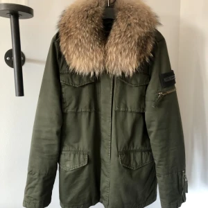 Khakigrön vinterjacka The Smirk - Vinterjacka med äkta pälskrage som går att plocka av om man vill det. Storlek M.  Går att dra åt på ryggen för att få jackan lite mer figursydd.  Använd men fint skick.☺️ Hämtas i Kungsbacka eller skickas mot att köparen betalar fraktkostnad. 