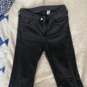 Urtvättade svarta bootcut jeans med midmidja - Älskade de här jeansen förut men brukar aldrig ha midwaist längre. Väldigt snygga jeans från HM köpta utomlands. Stretch och snygg urtvättning. Midja 36 och innerbenslängd 81