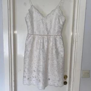 Vit klänning - Vit klänning från H&M i stl 40  Endast använd en gång och är i fint skick. Klänningen har ett vitt tyg under spetsen.