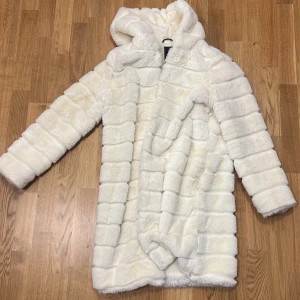 Lång teddyjacka - Lång teddykappa, går ner över rumpan. Varm och mysig. Gräddfärgad.
