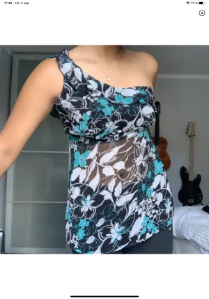 One Shoulder Topp - En asymmetrisk topp i mesh tyg. Har inbyggda kupor. I storlek XS-S. En volang gick nyligen av i tvätten (se bild) men det är bara att fästa den med några stygn. :)