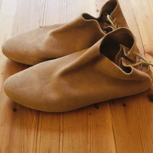 Mockaskor - Beige mocka skor med knytning bak, ett litet hål (se bild) höger sko, men inga andra defekter.