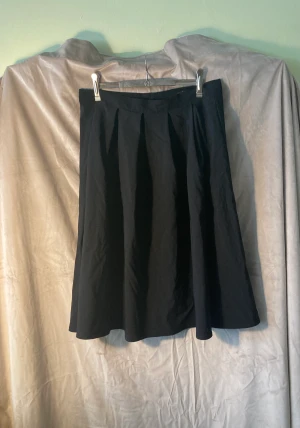 Daisy Dapper swing-kjol - Klassisk swingkjol i 50-talsstil från retro-märket Daisy Dapper. Strl L/40 (midja 80 cm). Dragkedja och knapp bak. Tillverkad i Sverige. Använd en gång. Har kostat 699 kr. 