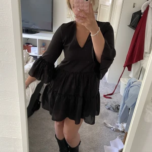 Svart klänning med volanger - Säljer nu min absoluta favoritklänning, som tyvärr blivit för liten över bysten. Väldigt fint skick. Köpt på NA-KD. Skulle säga att den även passar en 36 då den sitter löst.