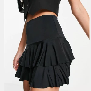 Svart minikjol - Svart minikjol med volanger och i stretchigt tyg, strl M 