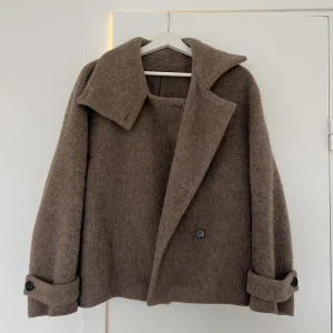 Kort ullkappa Arket  - Säljer denna korta ullkappa i en mörk beige färg. Väldigt sparsamt använd så fint skick. Stl 34 💞  Den sista bilden visar en identisk modell men slutsåld färg.   Material: 75% ull, 21% polyamid, 3% acrylic, 1% polyester