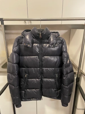 Moncler Maya - Säljer denna moncler maya jackan, som är i storlek 4 vilket motsvarar ungefär L, den är i bra skick förutom 2 skador som man kan se på andra bilden samt sista bilden! 