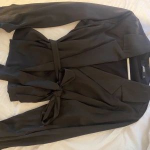 Siden skjorta med knytning - Svart siden liknande ”skjorta” Blus. Glasigt lent material. Ett band man knyter med i midjan samt ett inner band man kan knyta med för att säkerställa att inget åker upp. Finns knappar för handlederna. Bara att fråga för bättre bilder.