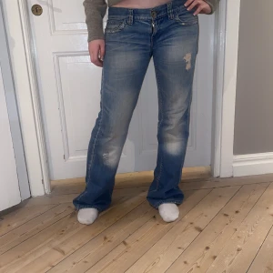 Lågmidjade jeans - Så coola lågmidjade jeans med slitningar. Utsvängd modell och sjukt smickrande passform🤩 Bra skick bortsett från slitningar vid hälarna (skriv för bild). Hör av dig vid funderingar och kolla in mina andra annonser❤️