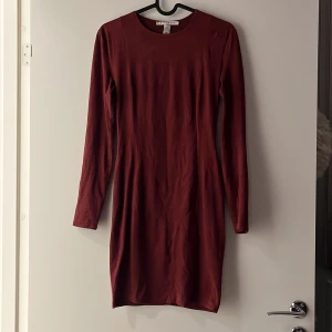 Klänning S - Långärmad klänning i ”mocka/suede” material. Knälång. Figursydd Nelly Vinröd Storlek: 36/S  Sparsamt använd 