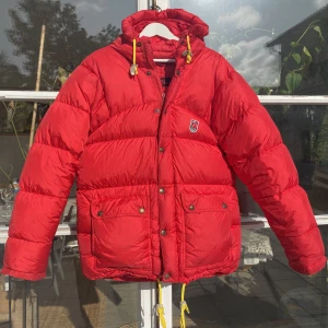 Fjällräven expedition Down lite Red Jacket - Hej, säljer tjejens väldigt populära röda Fjällräven vinterjacka i bra skick. Storlek XS men kan passa allt från 160-180 cm beroende på storleksperferens. Finns en liten defekt, bild i DM. Nypris över 7000kr. Pris kan diskuteras. Hör av dig vid frågor. 