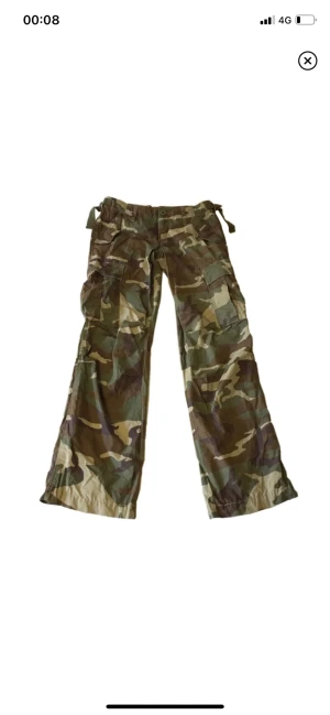 Kamouflage byxor/ cargobyxor - Snygga lågmidjade cargobyxor! Köpta på plick men passar tyvärr inte mig (inga bilder på) 100% bomull, midjemått 72cm, innerbensmått 78cm (OBS knappen där fram är lite lös men går lätt att sy fast om den skulle trilla av! Annars felfri)