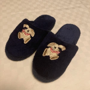 Mörkblå Tofflor - Mörkblå tofflor som är mjuka i sulan och ger en känsla av dämpning som gör det skönt att gå i dem 💙Det är en söt liten broderad kanin på varje toffla! Storleken står som L, men passar mig som brukar ha storlek 38 i skor. Pris kan diskuteras! 🙌
