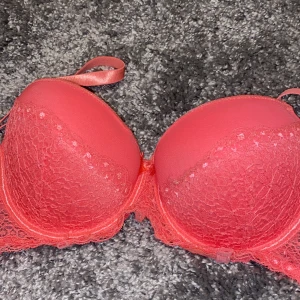 Bh - En super söt rosa bh med halv spets på. En rosa rosett mellan bysten. Inte push up men skulle ändå säga ett litet tryck upp ger den ändå. 