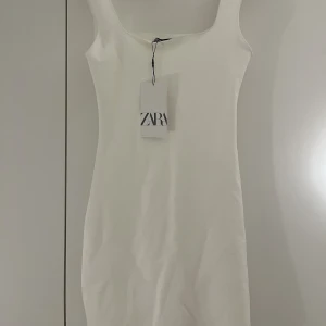 Vit klänning - Vit mini klänning ifrån zara. Figursydd så det sitter jätte fint på kroppen. storlek M men passar mig som brukar ha S. Helt ny med lappen kvar!