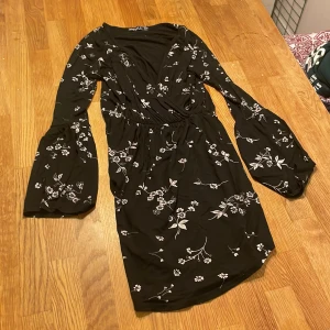 Svart klänning med vita blommor - Svart klänning med vita blommor, använd en gång, går ner till ungefär knäna då jag e 1.63cm. Inga håll eller fläckar