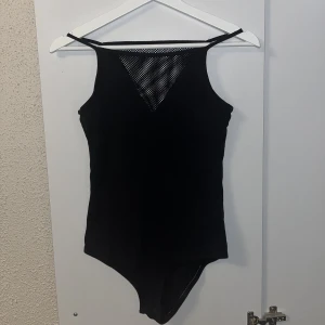 Svart bodysuit med nät🌸 - Oanvänd bodysuit med nätdetalj på toppen!🖤 Går att öppna och stänga där nere med 2 knappar, men går faktiskt att ha bodyn som en vanlig topp utan att behöva knäppa den ifall man skulle vela det, då den sitter bra ändå!❣️