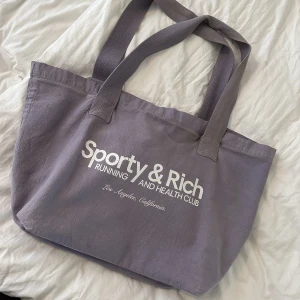 Sporty & Rich - Lila träningsväska från Sporty & Rich. Använd ett fåtal gånger.  Sömmen har gått upp lite på ena bandet så den är lite lös.