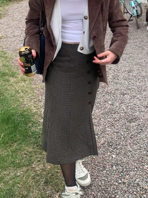 Brun midikjol  - En mönstrad midikjol i brunt med slits och knappar. Perfekt nu till hösten! 