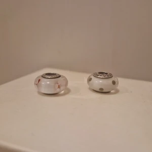 Pandora berlocker 2 st - 2 st original Pandora berlocker. En med prickar och en med rosa blommor.